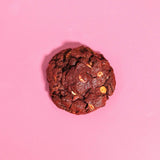 Red Velvet New York Cookie with white chocolate chips on a pink background by Crumbs & Doilies.